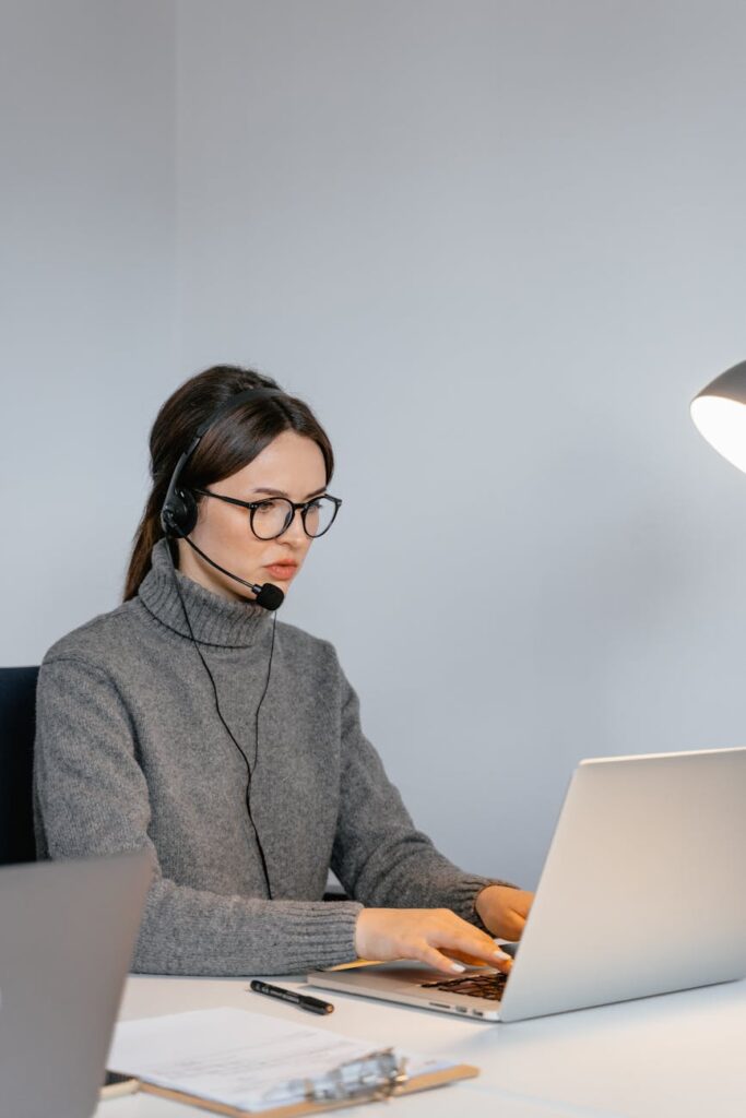 Focused woman in office with headset, providing customer support on laptop.